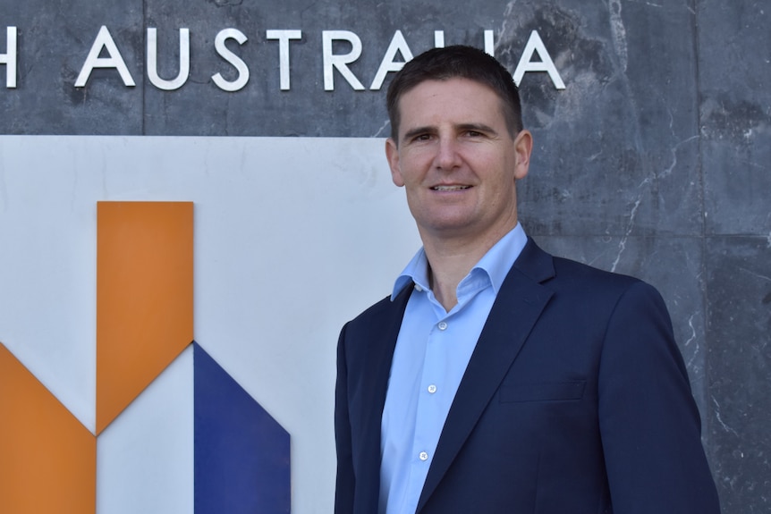 A man standing in front of a wall with the Master Builders logo on it.