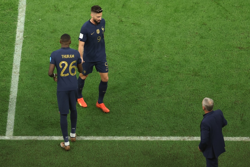 Soccer players wearing blue touch hands while walking around on a pitch