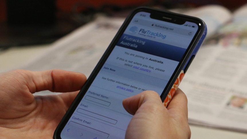Hands holding a phone which has the FluTracking website loaded.