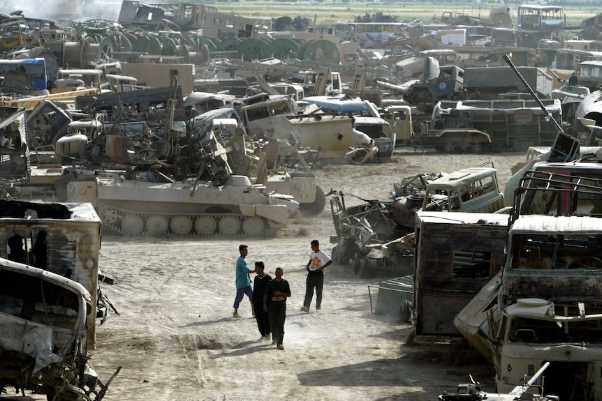 Men walk in wasteland of abandoned military tanks 