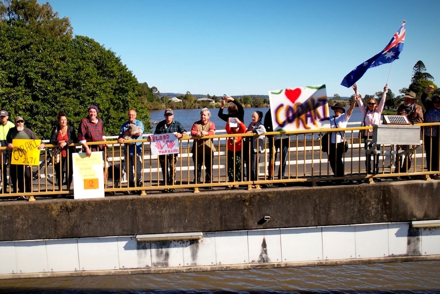 An aerial shot of a bridge with people standing along the edge, holding colourful signs.