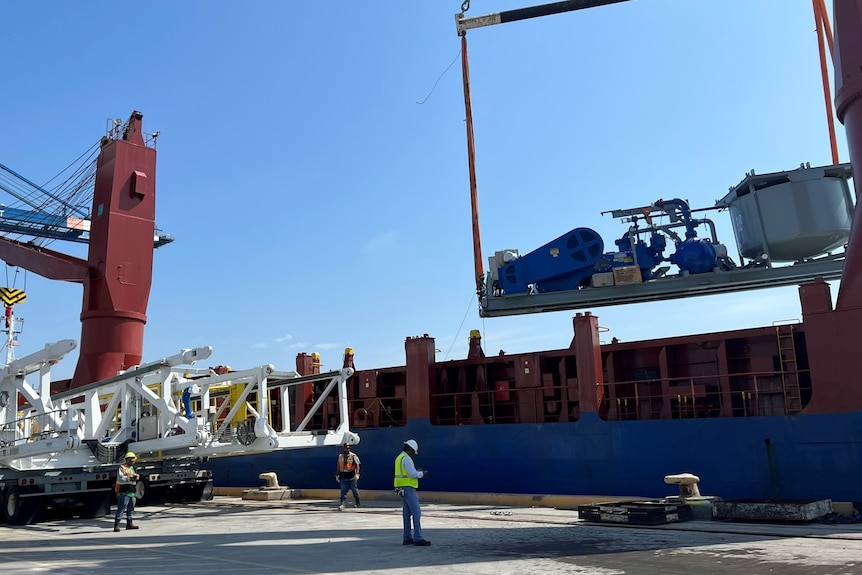 Drill rig equipment being loaded onto a ship at a port.