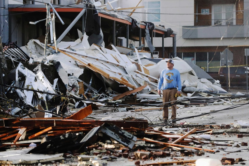 A man looks over buildings destroyed by storms.