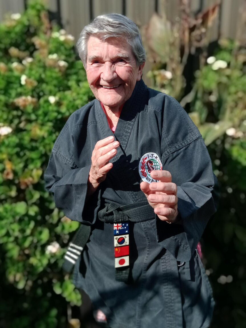 An elderly woman does a karate pose
