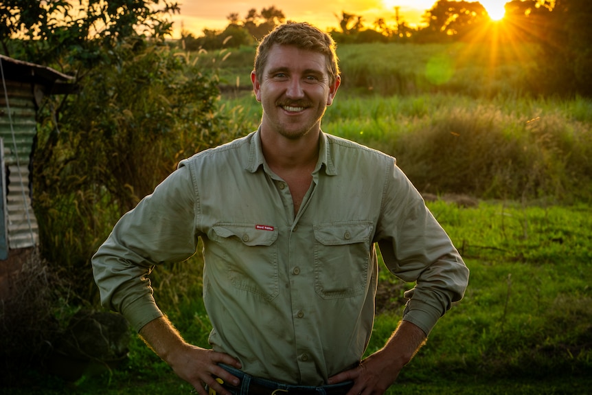 Image of a man standing in a field with sunlight filtering through.