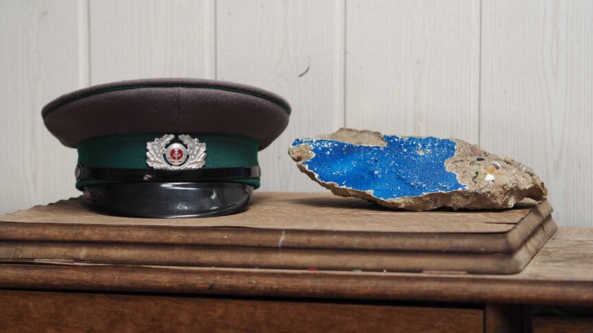 An East German guard's cap sitting next to a piece of broken off wall