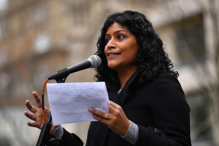 Samantha Ratnam holds a piece of paper while speaking to a crowd
