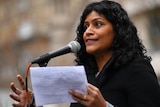 Samantha Ratnam holds a piece of paper while speaking to a crowd