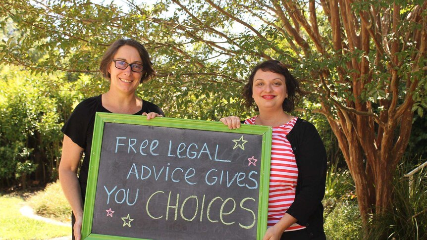 Julie from The Elizabeth Evatt Community Legal Centre and Kim from Legal Aid NSW hold a sign