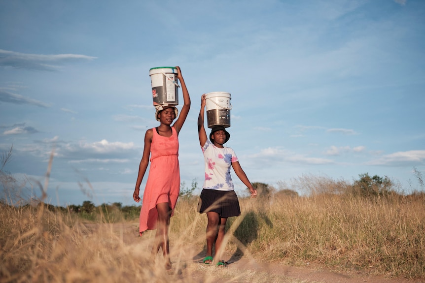 Tow girls carrying water on their heads in Zimbabwe