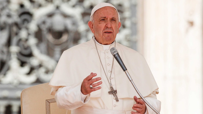 Pope Francis speaks into the microphone.