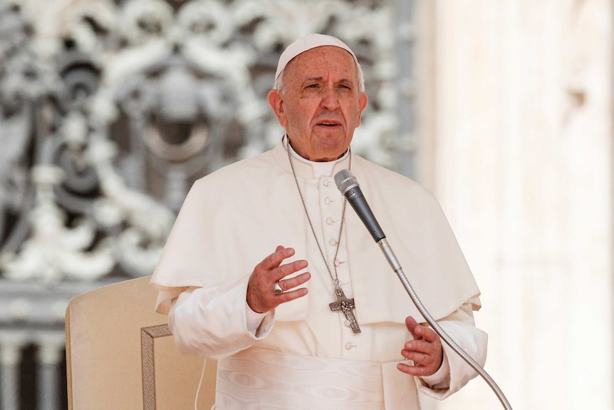 Pope Francis speaks into the microphone.