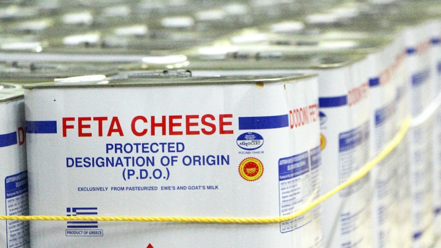 Boxes of feta cheese on the production line with "Protected Designation of Origin" written on the labels.