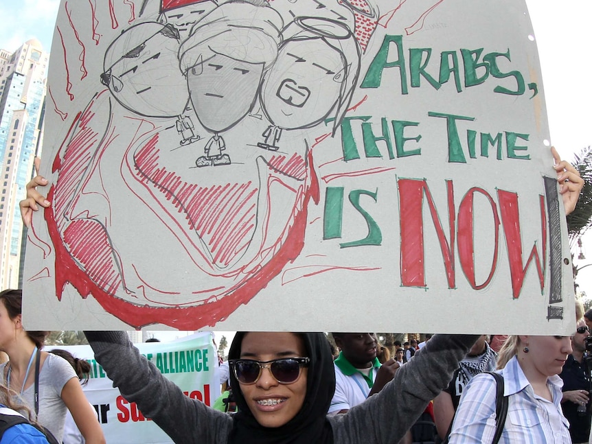 An activist carries a placard during a rally in Doha to demand urgent action on climate change.