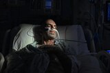 A man lying in bed, surrounded by tubes.