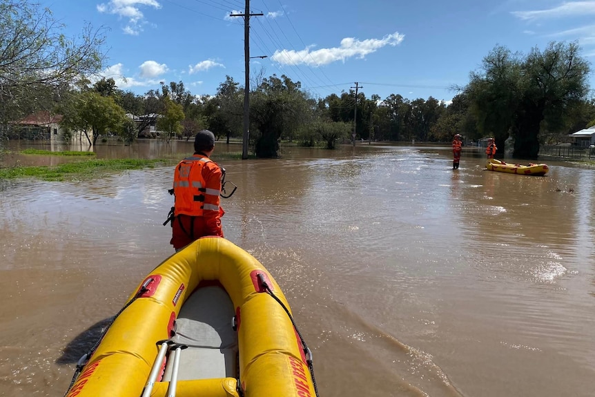 an emergency worker towing an inflatable boat over floodwaters