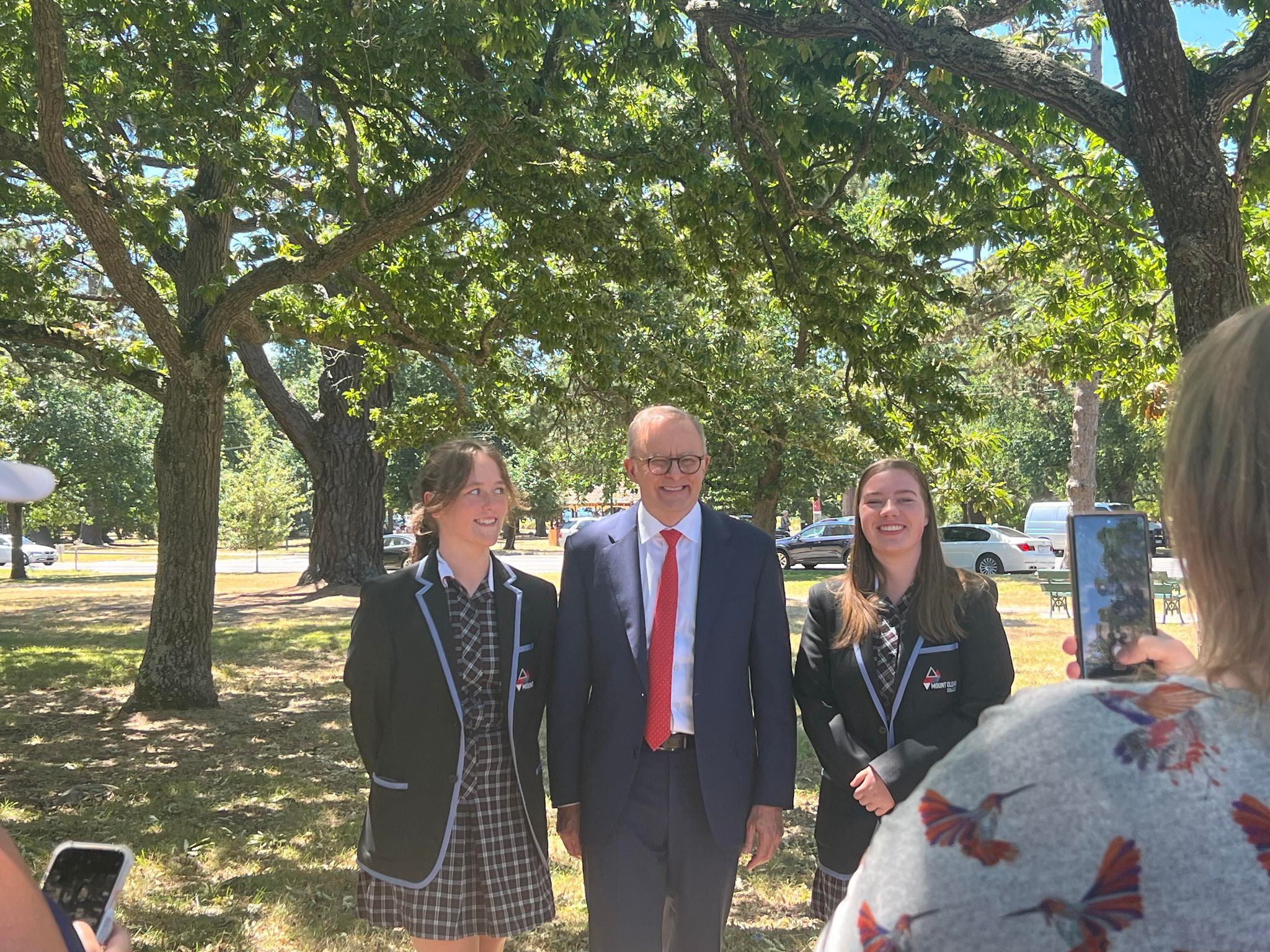a man smiles with two school kids for a photo