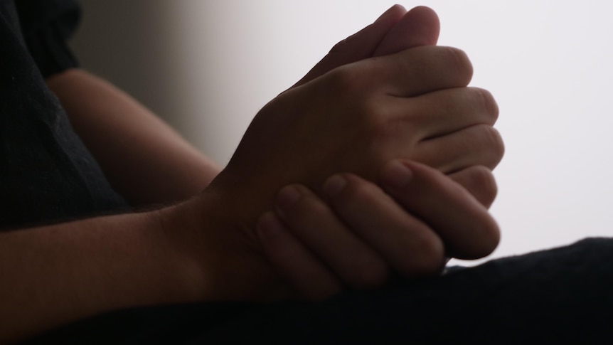 Close up shot of a woman's hands clasped on a lap