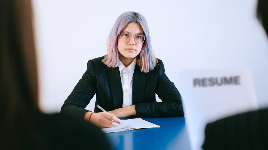 A woman with glasses taking notes at a meeting