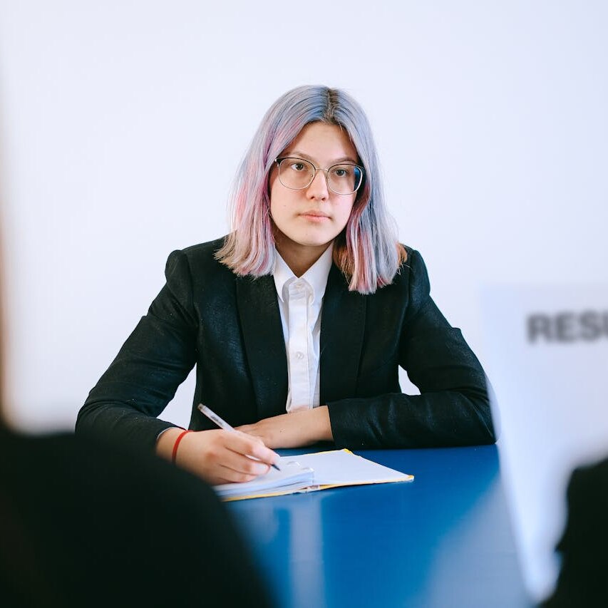 A woman with glasses taking notes at a meeting