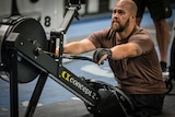 Man with no legs uses gym row machine at crossfit comp