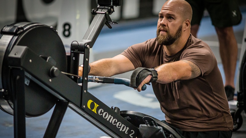 Man with no legs uses gym row machine at crossfit comp