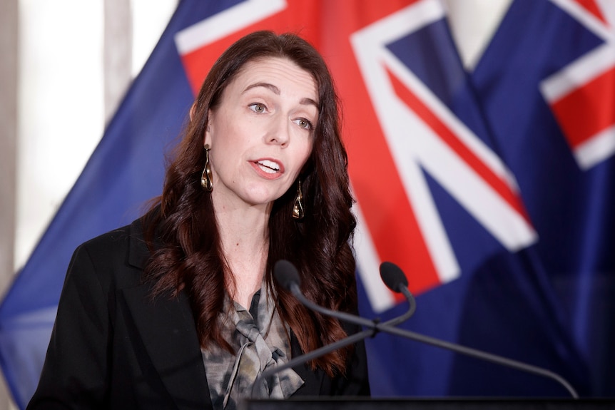 Le Premier ministre néo-zélandais Jacinda Ardern s'exprime devant un drapeau néo-zélandais