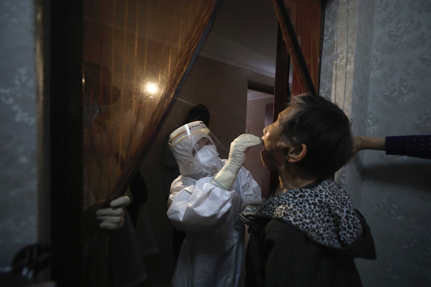 A medical worker takes a swab from a resident for the coronavirus test during home visits in Wuhan.