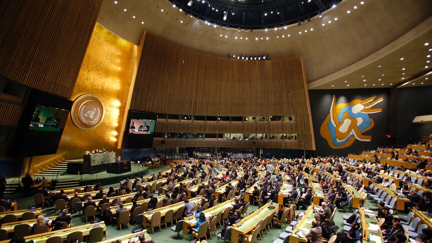 A wide shot of UN members sitting in the General Assembly at the UN headquarters