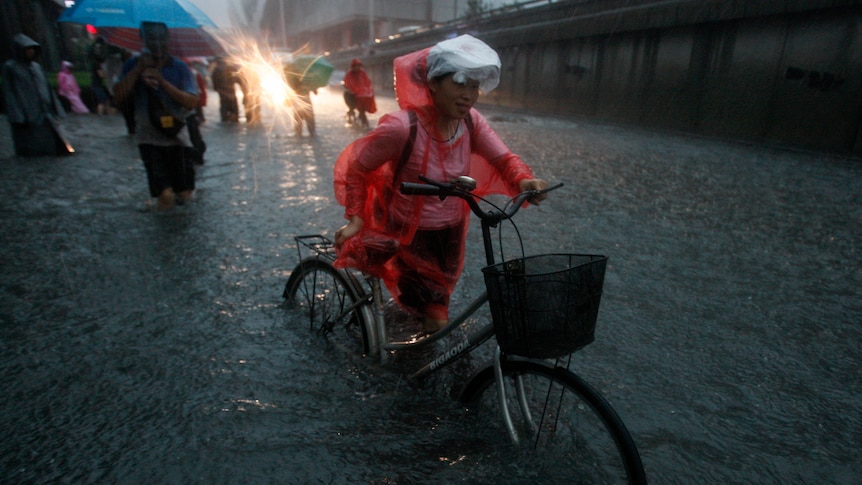 Woman pushes bike through Beijing floodwaters