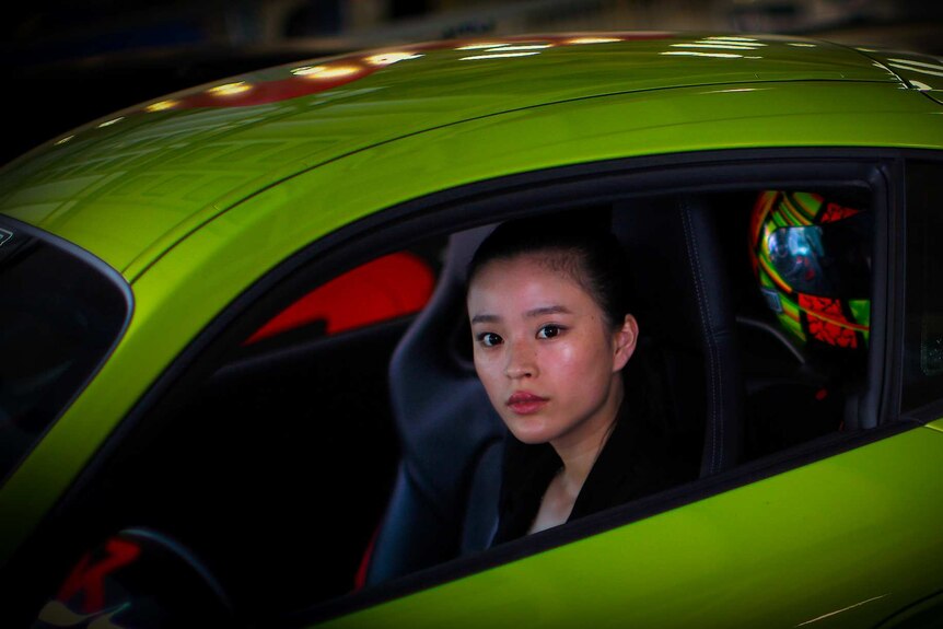 A Chinese woman sitting in a green car