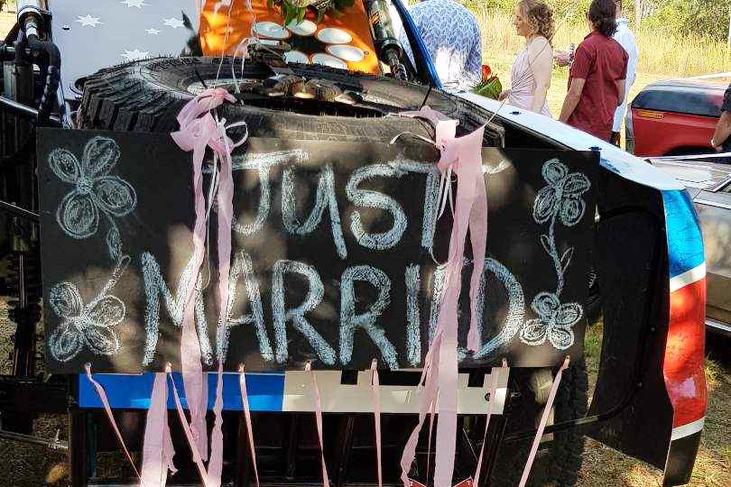 Just married sign with balloons, streamers and cans on the back of a trophy truck.