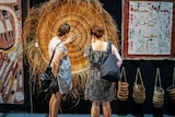 Shoppers closely analyse a piece at the art fair.