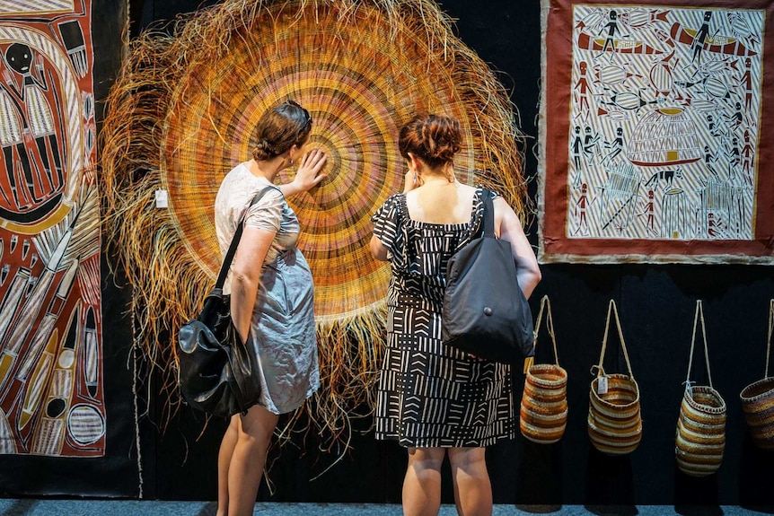 Shoppers closely analyse a piece at the art fair.