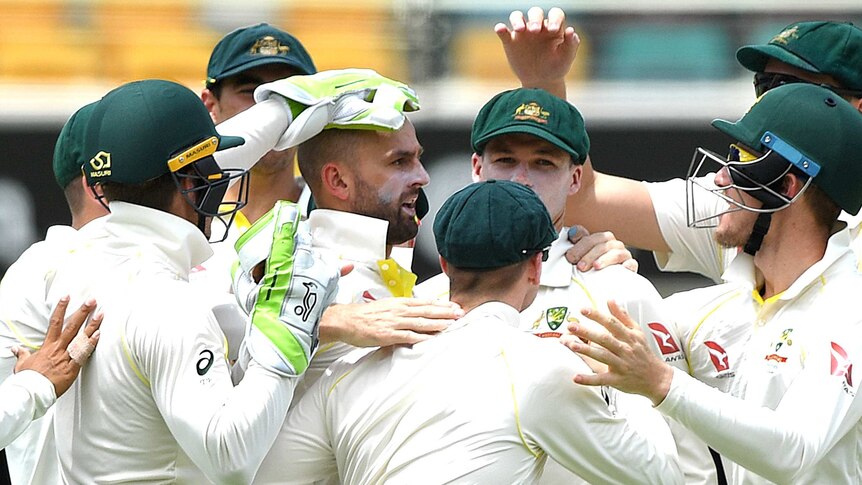 Australian players crowd around Nathan Lyon to congratulate him on his wicket.