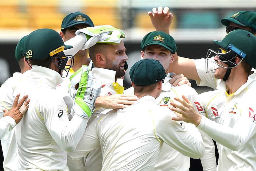 Australian players crowd around Nathan Lyon to congratulate him on his wicket.