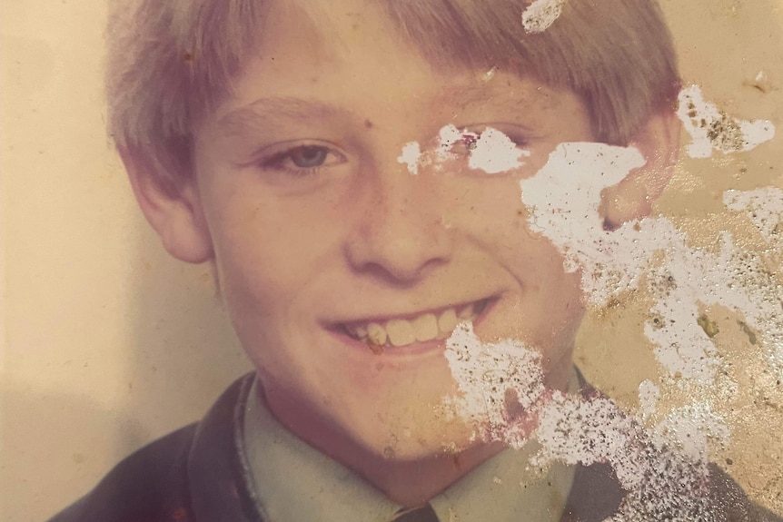 An old school photo of a young boy with blonde hair smiling.