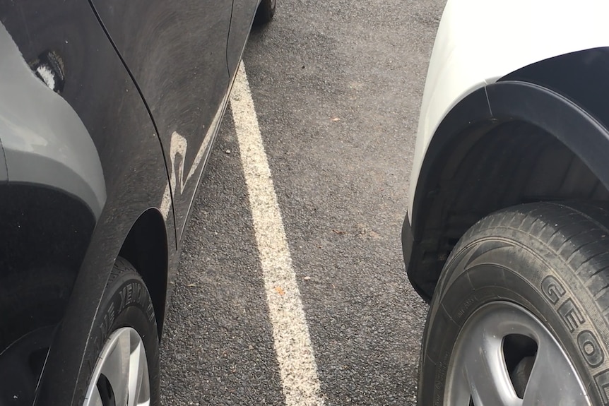 Close up of wheels of cars outside marked angle parking bays