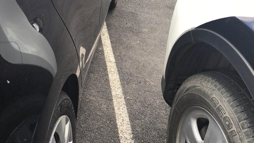 Close up of wheels of cars outside marked angle parking bays