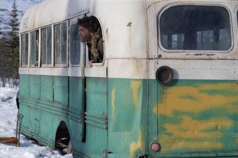 A man sticks his head out of the window of an old school bus.