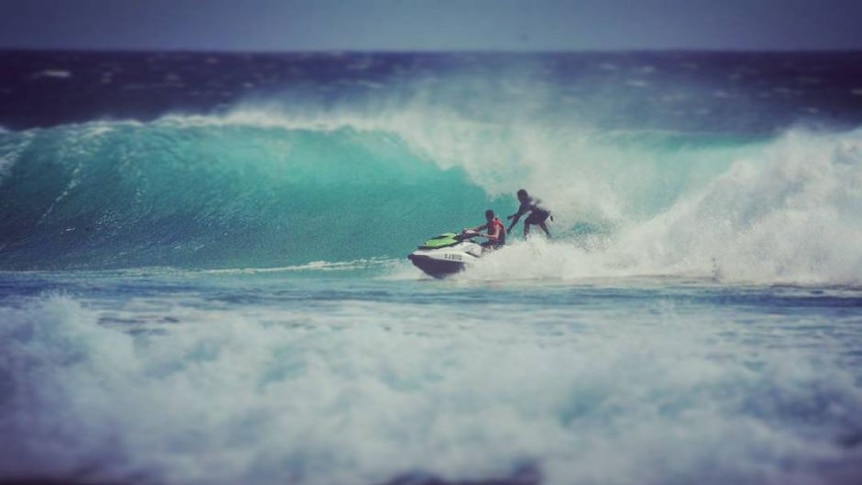 People riding a wave on a jet-ski