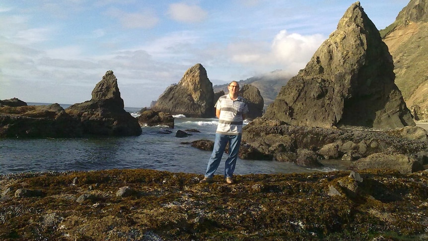 A photo of a man on a rocky coastline.