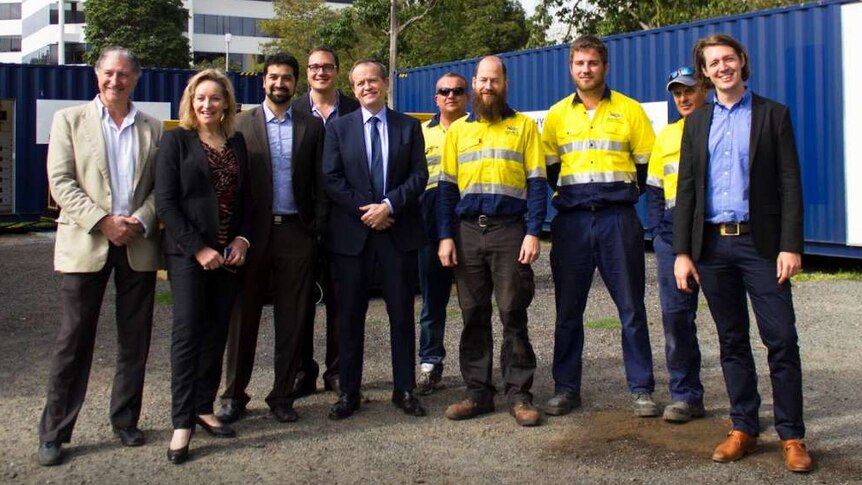 Alannah MacTiernan, Bill Shorten and people in suits and high-viz work gear pose at a work site.