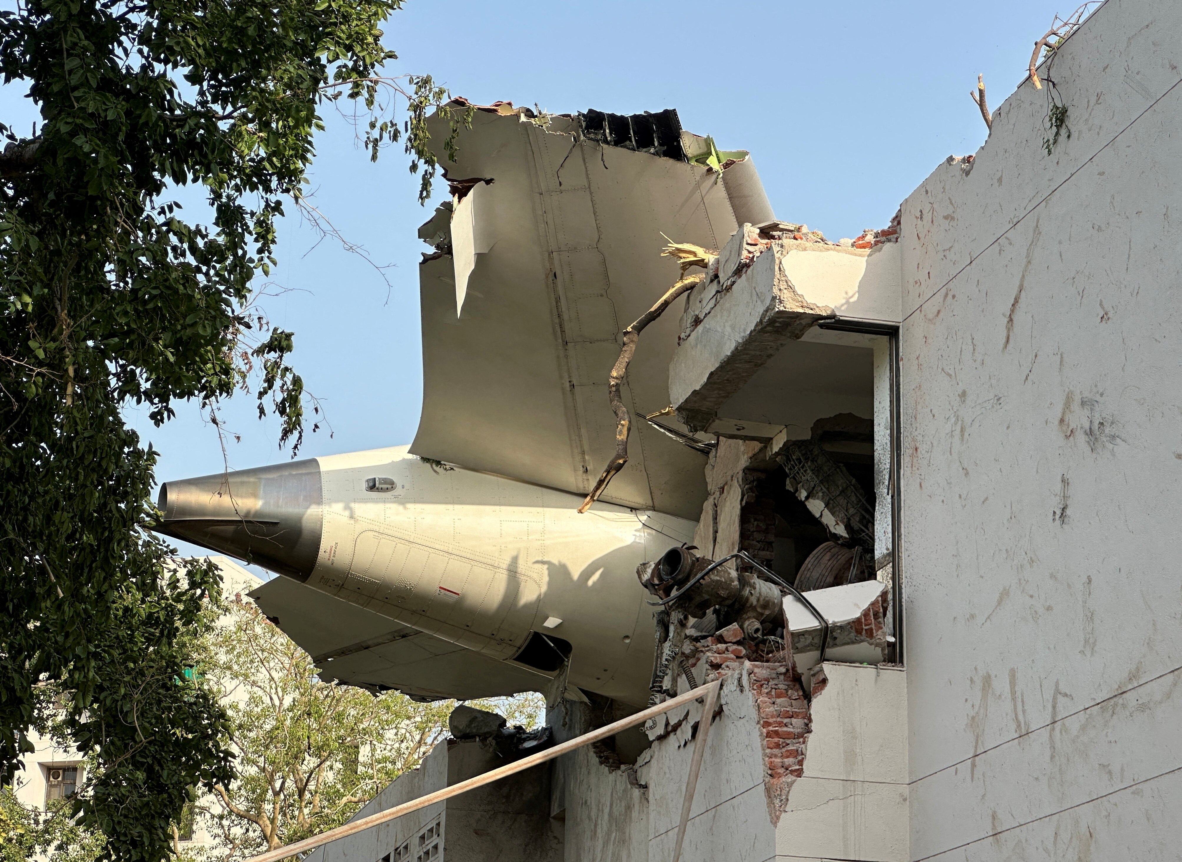 A tail of a plane that crashed is seen stuck on a building