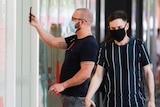 A man wearing a face mask uses his phone to scan into Safe WA.