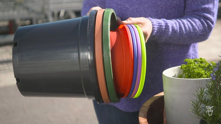 A person pulling apart a stack of coloured plastic pots