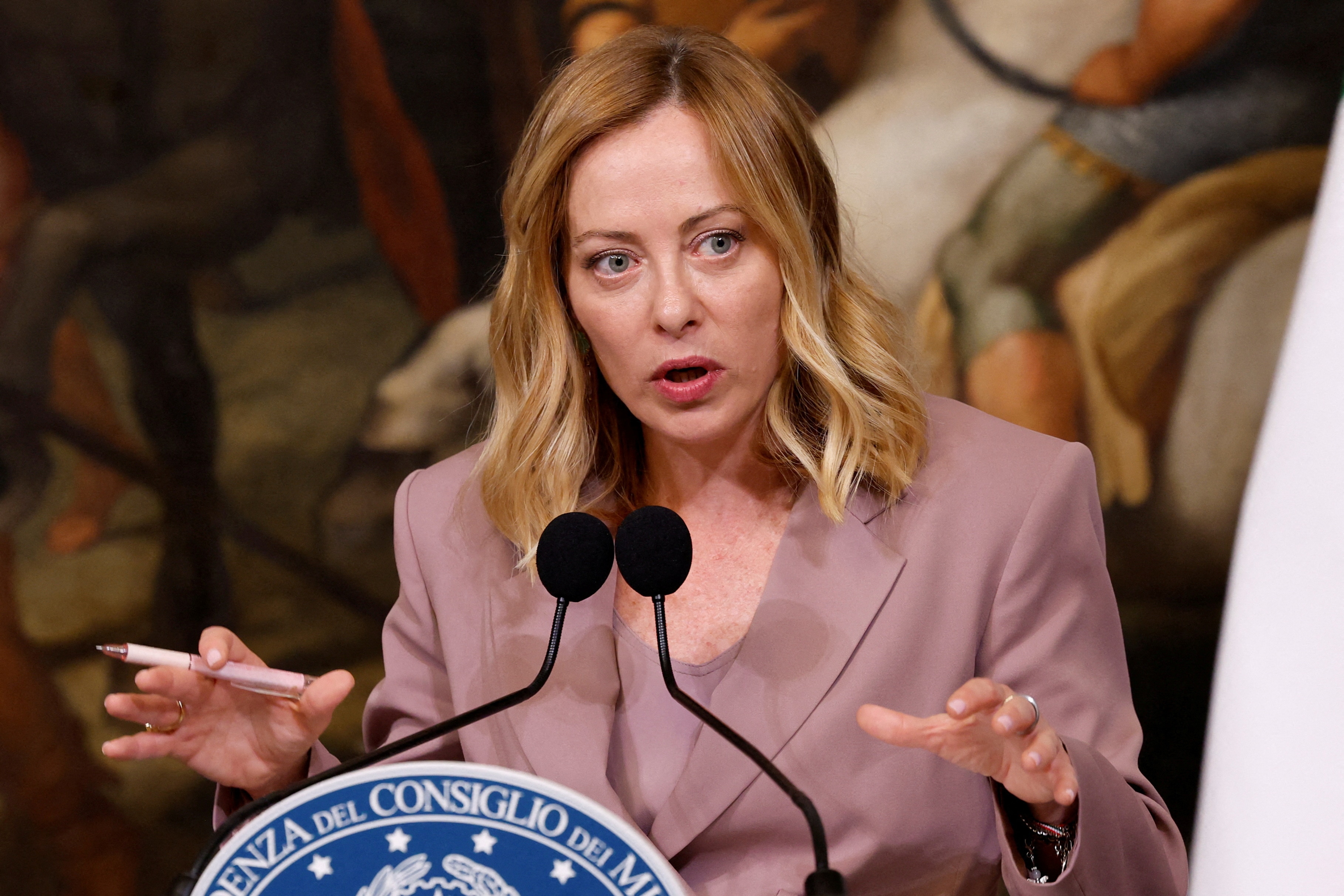 Giorgia Meloni speaking into two microphones.