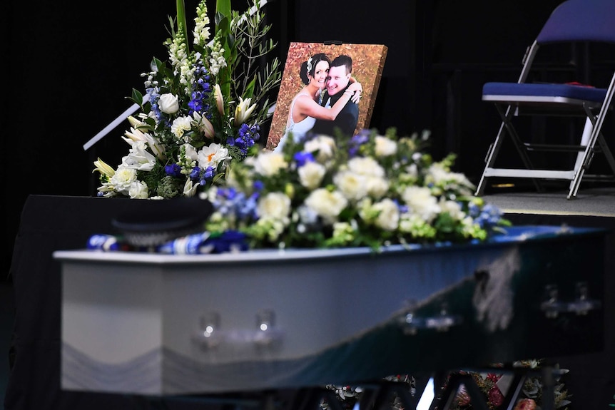 Senior Constable Brett Forte's casket with flowers and a photograph of Brett and his wife, Susi, on top