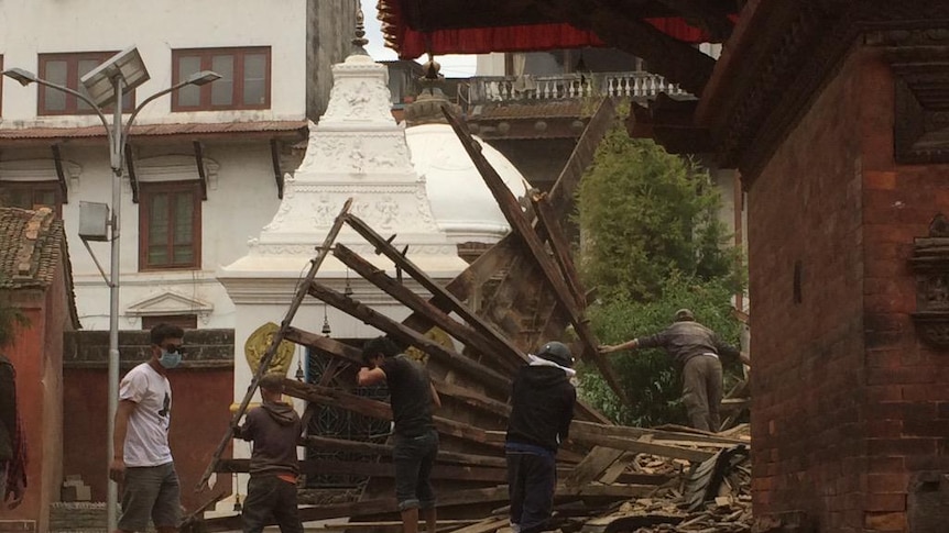 Volunteers clear away the frames of broken walls in Patan