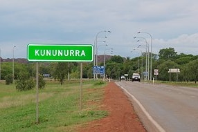 A  sign that reads 'Kununurra' by an outback road.